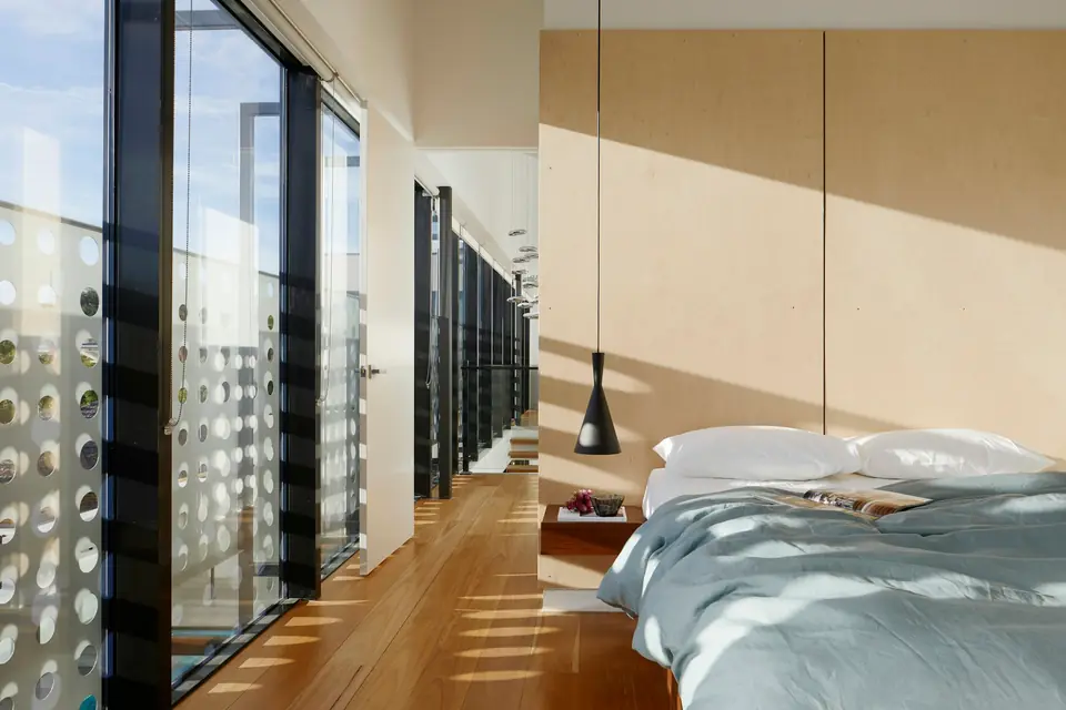 Primary bedroom with warm timber walls and floor-to-ceiling glass